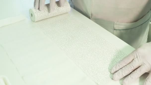 Молодой врач размотает рулон с полиуретановой лентой на столе в помещении . — стоковое видео