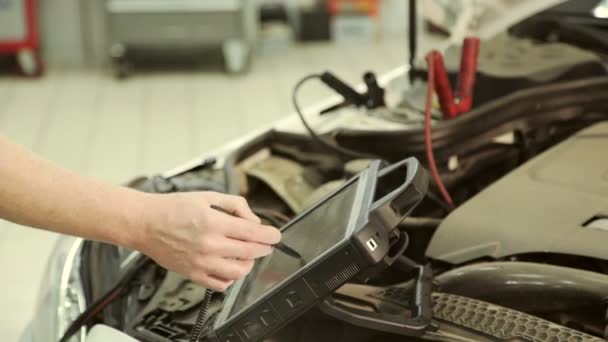 Em um mecânico de garagem usando computador conduz sintonia do motor de chip . — Vídeo de Stock