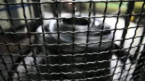 Spule mit Metalldraht dreht sich hinter Gitter an Maschine. — Stockvideo