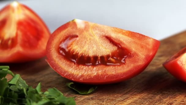 Cook está cortando fatia de tomate ao meio na mesa na cozinha em casa . — Vídeo de Stock