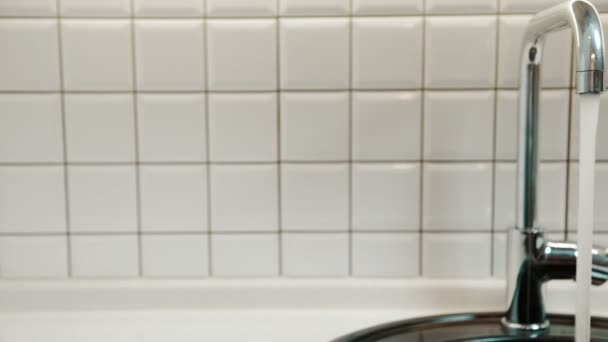 Sauberes Wasser fließt aus dem Wasserhahn im Badezimmer der Wohnung. — Stockvideo