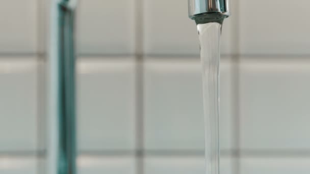 El agua pura fluye del grifo metálico en el baño en el apartamento . — Vídeo de stock