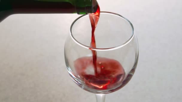 El hombre vierte vino tinto en vidrio de pie sobre la mesa en la cocina . — Vídeos de Stock