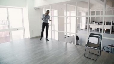 Genç adam telefonla, modern ofis etrafında yürüyüş konuşuyor.