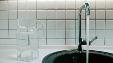 Adam musluk ve su akışını lavabo içine kapalı açar.