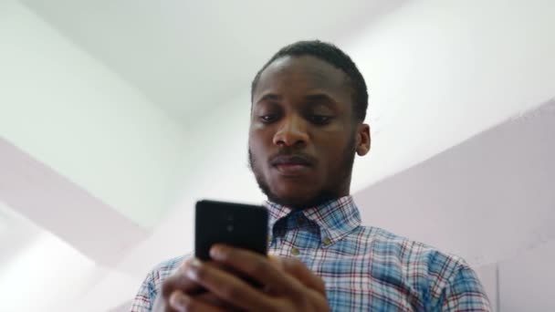 Африканский бизнесмен держит в руках телефон в современном офисе . — стоковое видео