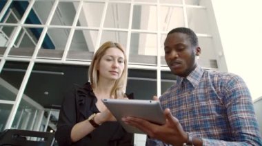 Genç meslektaşları modern ofiste otururken tablet kullanarak.