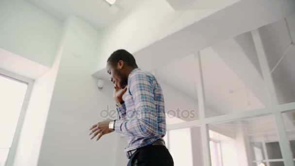 Портрет афроамериканского старшего дизайнера, разговаривающего по телефону в коридоре в яркой студии — стоковое видео