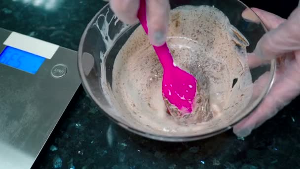 Close-up de um confeiteiro em luvas amassa uma nata de chocolate em uma tigela . — Vídeo de Stock