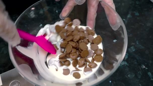 Крупным планом кусочки хоколата смешиваются с молоком в стеклянной чаше . — стоковое видео
