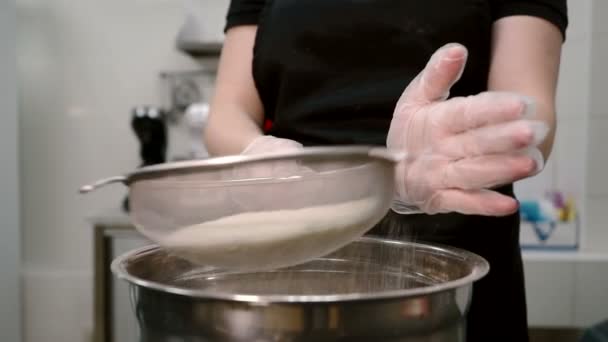 Giovane donna setaccia farina utilizzando setaccio in casa cucina al chiuso . — Video Stock