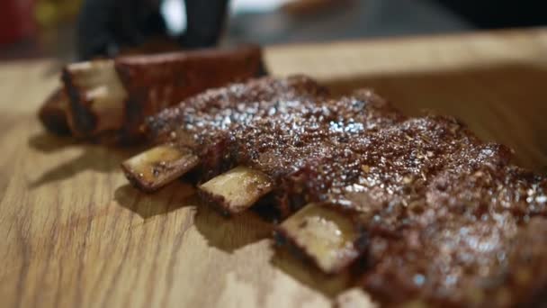 Joven cocinero está poniendo costillas de cerdo en capas en la cocina del restaurante . — Vídeo de stock