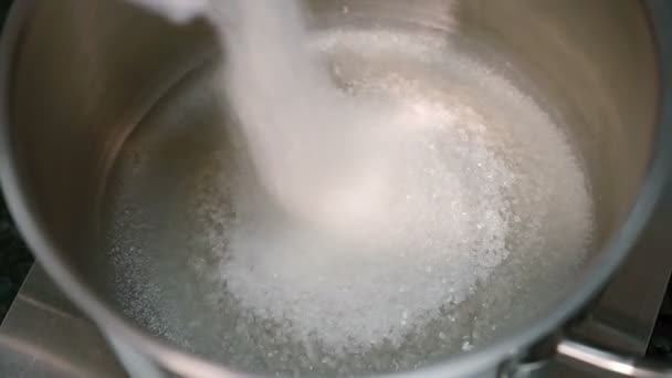 Крупним планом цукор розкидають у сталеву миску з водою на дні для приготування торта на кухні — стокове відео
