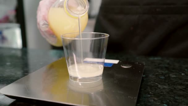 Nahaufnahme von Zitronensaft wird von der Flasche auf das Glas in der Küche gegossen. — Stockvideo