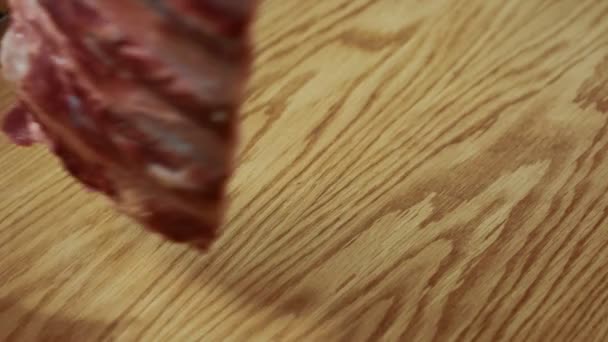 Beef ribs are being put to the wooden cutting board on the kitchen of restaurant, close up. — Stock Video