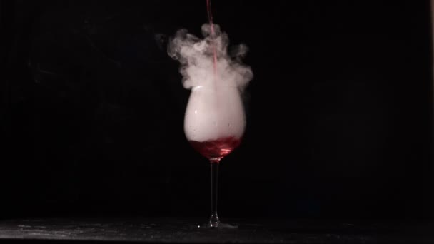 Persoon giet wijn in het glas met vloeibare stikstof op zwarte achtergrond. — Stockvideo