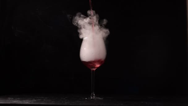 Person pours wine into glass with liquid nitrogen on black background. — Stock Video