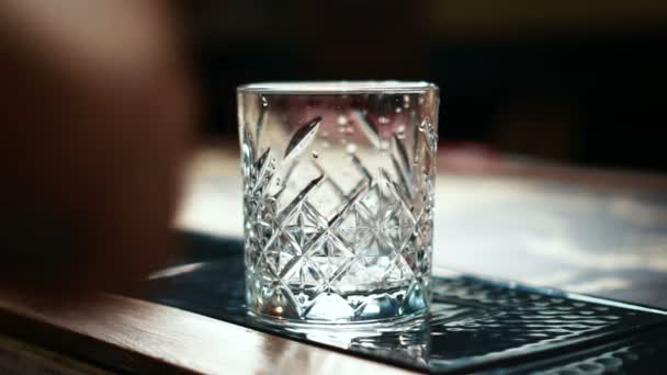 Barman nalévá kusy ledu do sklenice na stole v noci bar uvnitř. — Stock video