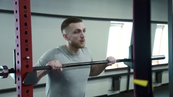 Hombre en el entrenamiento en el gimnasio toma una varilla y comienza a levantar el peso . — Vídeo de stock