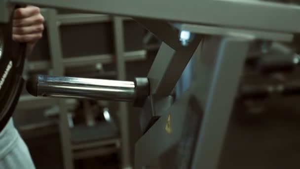 Primer plano de la placa negra, que se está poniendo en la barra de acero en el gimnasio . — Vídeos de Stock