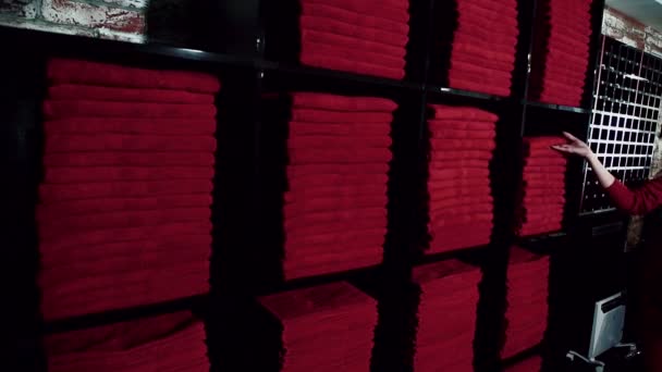 Jeune femme prend serviette rouge de stock en étagères noires dans le centre sportif de luxe, au ralenti . — Video