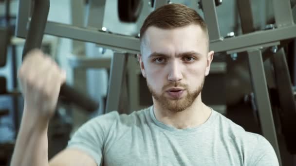 Portret silnego człowieka, który ściąga wagi z jednej strony na maszynie szkolenia. — Wideo stockowe