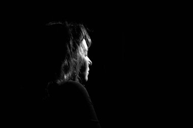 Profilde siluet siyah arka planda yalnız ve üzgün bir kız.