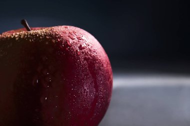 Koyu arkaplanda su damlalarında sulu, taze kırmızı bir elma. Karanlıkta fotoğraf..
