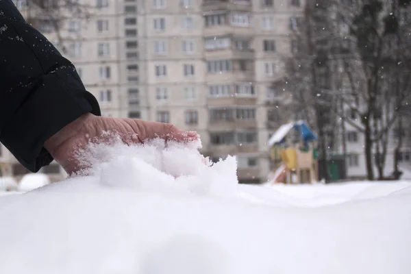 Hand in the snow on a photo of a high-rise building and a playground
