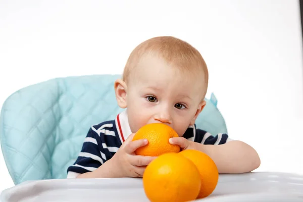 Веселый Мальчик Сидит Детском Кресле Ест Апельсины Белом Фоне Свежие — стоковое фото