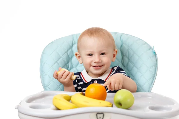 Веселый маленький мальчик ест свежие бананы на белом фоне — стоковое фото