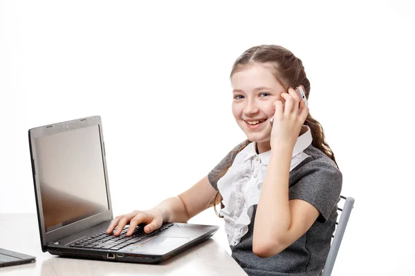 Estudante bonito sentado em um laptop e falando ao telefone em um fundo branco — Fotografia de Stock