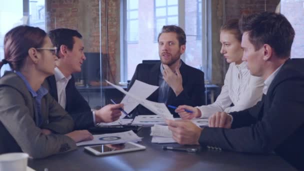 Parceiros de negócios discutindo documentos e ideias na reunião — Vídeo de Stock