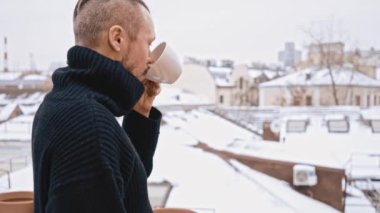 Bıyık kahve içenlere çatı üzerinde olan genç adam. Kış