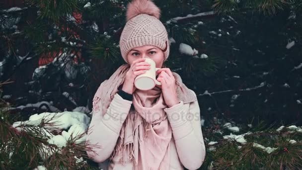 Frau trinkt an einem verschneiten Wintermorgen im Freien heißen Tee oder Kaffee aus einer Tasse. — Stockvideo