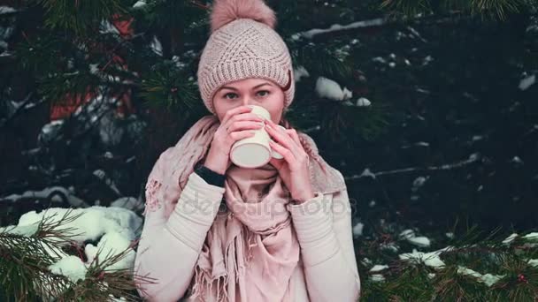 Kvinna drycker varma te eller kaffe ur en kopp på snöiga vintermorgon utomhus. — Stockvideo