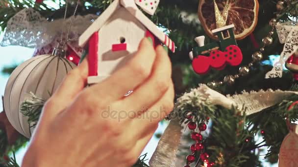 Neues Haus am Weihnachtsbaum. Hypothek. Eine junge Frau legt Spielzeug auf einen Weihnachtsbaum. Zeitlupe — Stockvideo