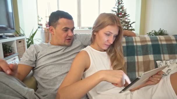 Junges Paar mit Tablet-PC zu Hause. Weihnachtszeit. Zeitlupe — Stockvideo