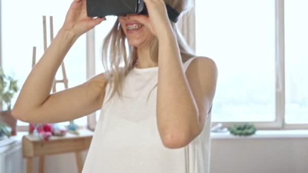 Slow motion of blonde woman in white space trying virtual reality glasses. — Stock Video