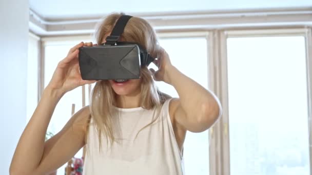 Slow motion of blonde woman in white space trying virtual reality glasses. — Stock Video