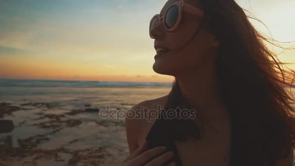 Nahaufnahme Porträt einer schönen jungen Frau, die bei Sonnenuntergang am tropischen Strand lächelt — Stockvideo
