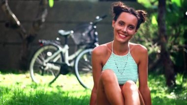 Bisikletini arkasında'nın bahçesinde gülümseyen genç güzel kadın durumda. Güneşli gün