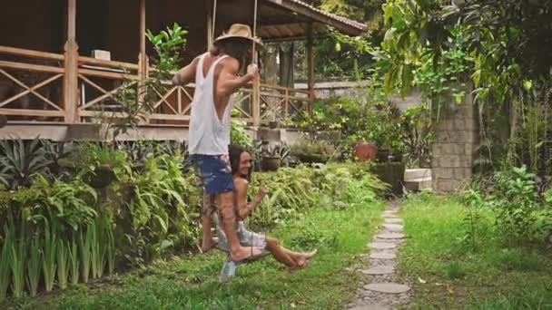 Happy loving couple sitting in swing and talking while in garden — Stock Video