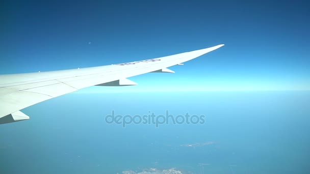 飛行中の旅客機。カラフルな土地上空を飛んでいる飛行機の翼 — ストック動画