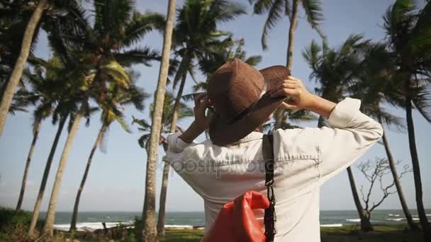 Молода жінка з рюкзаком і капелюхом серед кокосових долонь щаслива новими пригодами. Відкрийте для себе. Час пригод . — стокове відео