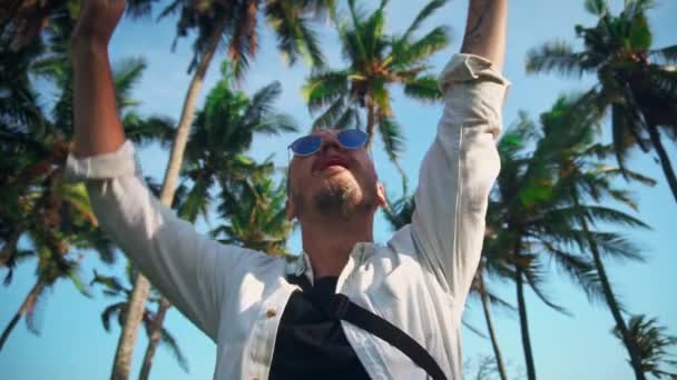 Un joven activo en un sombrero y con una mochila por el bien de las vacaciones de cocoteros está feliz por las nuevas aventuras. Descubridor. Tiempo de aventura . — Vídeo de stock