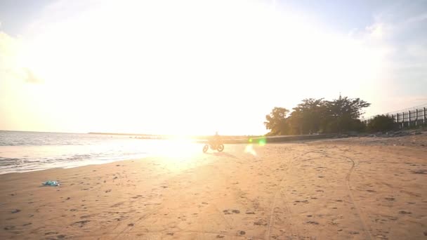 Motoros vezetés a motorkerékpár, a strandon során naplemente — Stock videók