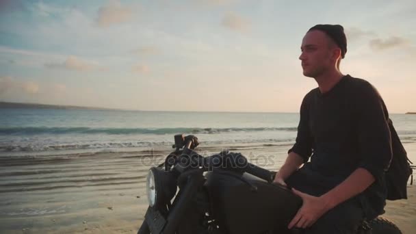 Motociclista conduciendo su moto en la playa al atardecer — Vídeos de Stock