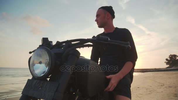 Мотоцикліст їде на мотоциклі на пляжі під час заходу сонця — стокове відео