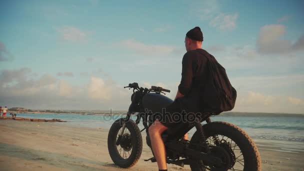 Motocyklista jízdy jeho motorce na pláži při západu slunce — Stock video